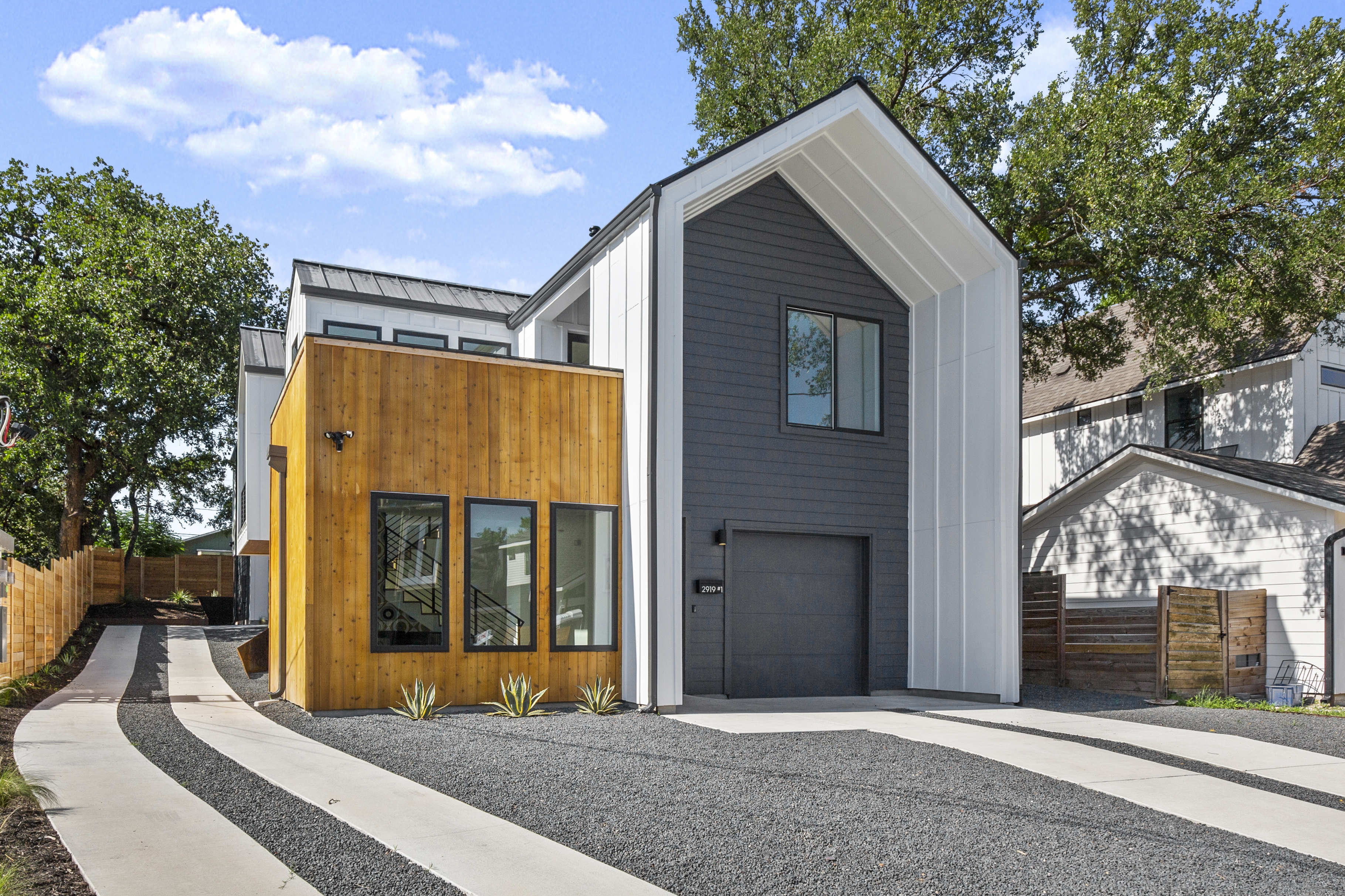 Outside of a custom built home made out of wood and gray and white panels in Austin, TX.