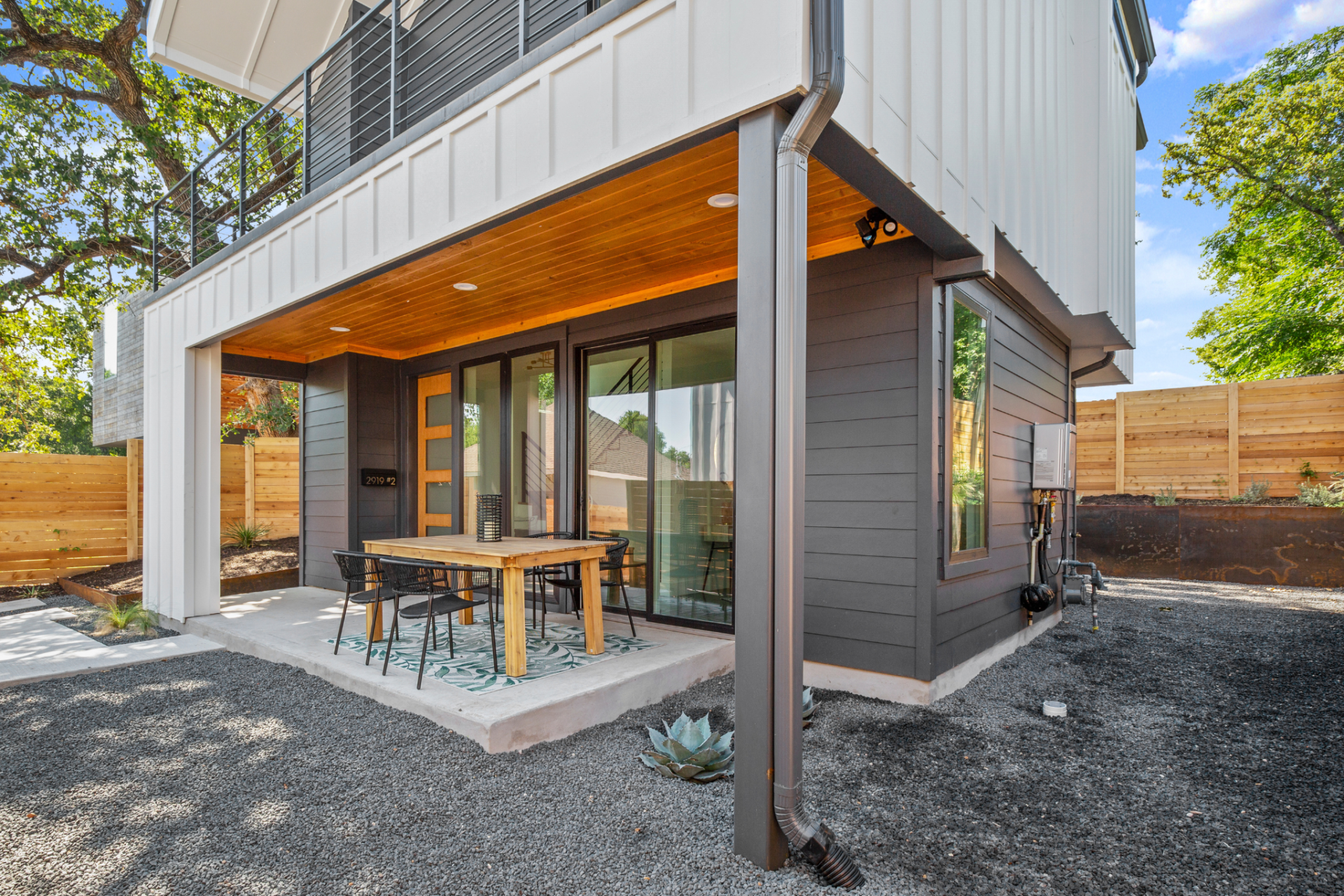 New 2-story construction sneak peak through sliding glass doors and kitchen table; overhead balcony, and large glass windows.