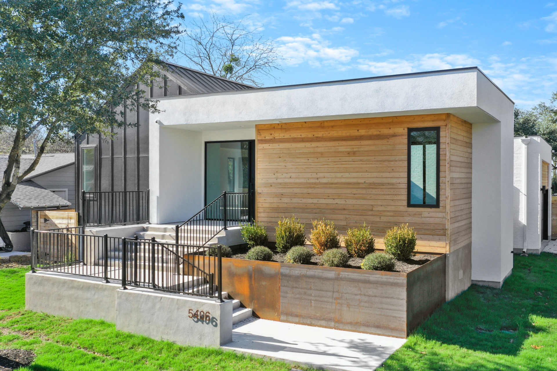 Exterior shot of a luxurious 2-story 3 bed, 2 bath home with large windows, native Texas plants, and wood detailing in Austin, TX.